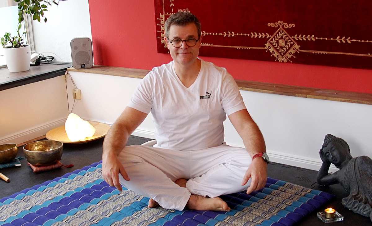 Hermann lächelt in weißer Arbeitskleidung am Behandlungsplatz bei Thai Yoga Eifel